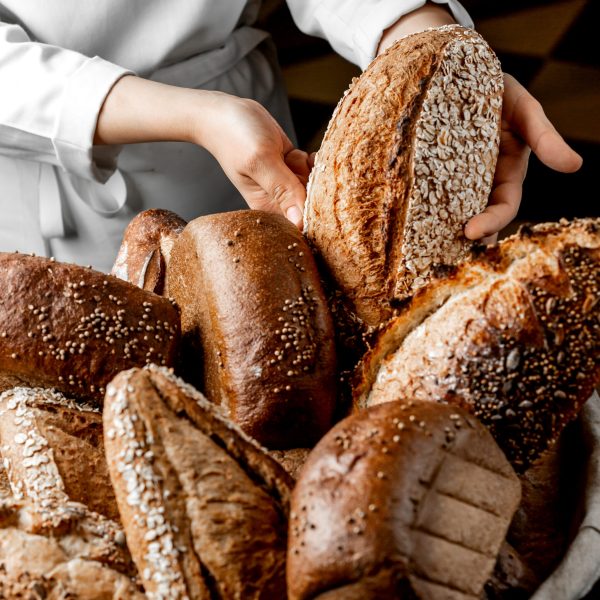woman putting whole grain bread bun among other breads
